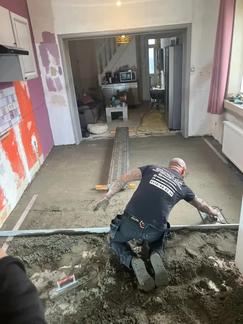 Artisan travaillant sur une chape dans une pièce en rénovation.
