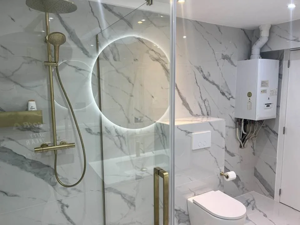 Salle de bain avec douche vitrée, carrelage effet marbre et équipements sanitaires.